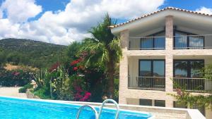una villa con piscina di fronte a una casa di Ferienhaus in Ermioni mit Grill, gemeinschaftlichem Pool und Terrasse a Thermisía