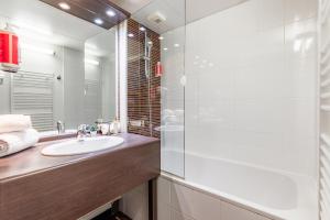 a bathroom with a sink and a large mirror at Appart’City Confort Nantes Ouest Saint-Herblain in Saint-Herblain