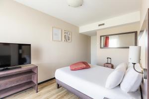 Schlafzimmer mit einem Bett und einem Flachbild-TV in der Unterkunft Appart’City Confort Nantes Ouest Saint-Herblain in Saint-Herblain