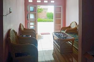 sala de estar con sillas, mesa y puerta en RedDoorz at Pantai Panjang Bengkulu 2 en Bengkulu