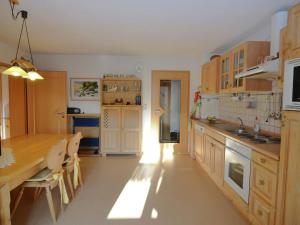 a kitchen with wooden cabinets and a table and a counter at Comfort apartment with balcony in the beautiful Bavarian Forest in Drachselsried