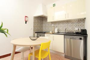 een kleine keuken met een tafel en gele stoelen bij Casa Sebastião in Faro