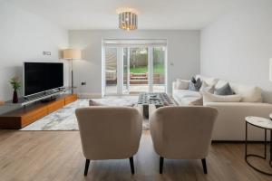 ein Wohnzimmer mit einem Sofa, Stühlen und einem TV in der Unterkunft Pass the Keys Bright Modern - Lovely Garden in Chesham