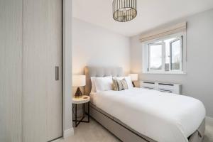 ein weißes Schlafzimmer mit einem weißen Bett und einem Fenster in der Unterkunft Pass the Keys Bright Modern - Lovely Garden in Chesham