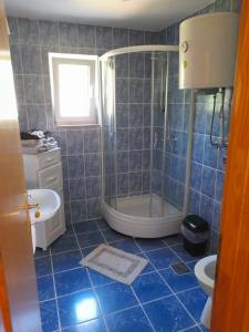 y baño de azulejos azules con ducha y lavamanos. en Sarajevo Holiday Apartment 3, en Sarajevo