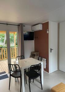 a dining room with a white table and black chairs at Familial central lac in Biscarrosse