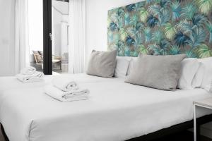 a bedroom with a white bed with a tropical wallpaper at Apartamentos de Isabella in Granada