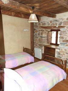 duas camas num quarto com uma parede de pedra em Casa Aurora em San Esteban del Toral