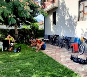 a group of people sitting on the grass next to a building at Bus Station Hostel in Peje