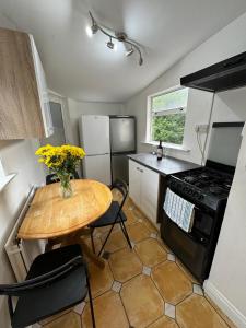 a small kitchen with a wooden table and a table with yellow flowers at Nice Triple Room at 2 Iveragh Rd-7 in Dublin