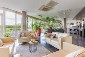 una sala de estar con sofás, plantas y ventanas en Appart’City Confort Nantes Ouest Saint-Herblain en Saint-Herblain