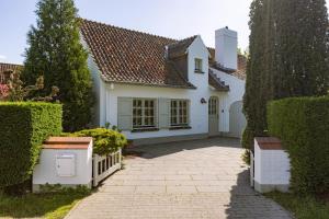 ein weißes Haus mit einem Tor und einer Auffahrt in der Unterkunft Maison Philippe in Koksijde