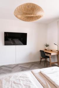 1 dormitorio con cama, escritorio y lámpara de araña en TRIMOSA Apartments - cozy, modern und citynah, en Trierweiler