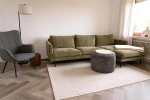 ein Wohnzimmer mit einem Sofa und einem Stuhl in der Unterkunft TRIMOSA Apartments - cozy, modern und citynah in Trierweiler