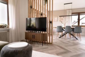 a living room with a flat screen tv on a wooden stand at TRIMOSA Apartments - cozy, modern und citynah in Trierweiler