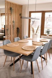 een eetkamer met een houten tafel en stoelen bij TRIMOSA Apartments - cozy, modern und citynah in Trierweiler