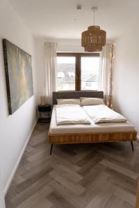 Schlafzimmer mit einem Bett und einem Fenster in der Unterkunft TRIMOSA Apartments - cozy, modern und citynah in Trierweiler
