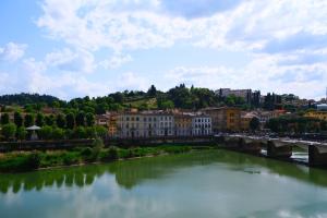 um rio numa cidade com edifícios e uma ponte em Mamo Florence - Tintori Luxury Palace em Florença