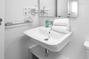 a white bathroom with a sink and towels at Apartamentos de Isabella in Granada