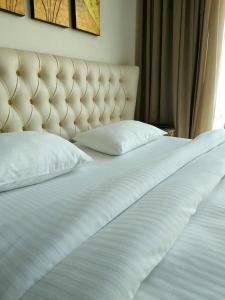 a white bed with two pillows and a tufted headboard at King David Residence in Tbilisi City