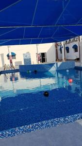 uma piscina com um guarda-chuva azul e bolas dentro em Sharjah International Airport Hotel em Sharjah