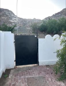 une grande porte noire dans une clôture blanche dans l'établissement Old Muscat, à Kalbūh