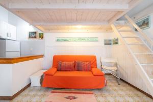 een oranje bank in een kamer met een trap bij Monolocale Ginetto in Calasetta
