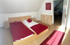 una camera con letto in legno e coperta rossa di Gösser BACHGASSLHOF -- Bed and Breakfast -- Apartments a Leoben