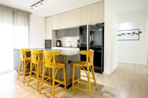 une cuisine avec des tabourets jaunes autour d'un comptoir de cuisine dans l'établissement Spacious Apartment – fully furnished and equipped, à Hadera