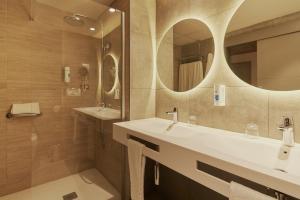 a bathroom with two sinks and a mirror at Gloria Palace San Agustín Thalasso & Hotel in San Agustin