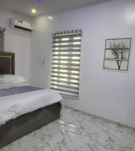 biała sypialnia z łóżkiem i oknem w obiekcie PLOT 36 APARTMENT w mieście Lekki