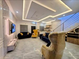 a living room with couches and chairs and a staircase at PLOT 36 APARTMENT in Lekki