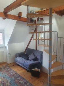 a living room with a blue couch and a spiral staircase at Ferienwohnung Katrin in Mettlach