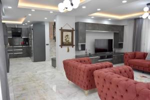 uma sala de estar com cadeiras vermelhas e uma televisão de ecrã plano em gb’sluxuryhomes Antalya’daki eviniz em Belek