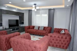 Sala de estar con 2 sofás rojos y TV en gb’sluxuryhomes Antalya’daki eviniz, en Belek