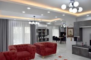 a living room with two red chairs and a kitchen at gb’sluxuryhomes Antalya’daki eviniz in Belek