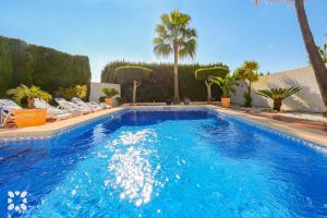 ein großer Swimmingpool mit Stühlen und Palmen in der Unterkunft Villa Aurora by Abahana Villas in Benissa
