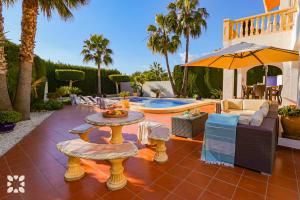 eine Terrasse mit Tisch und Sonnenschirm und ein Pool in der Unterkunft Villa Aurora by Abahana Villas in Benissa