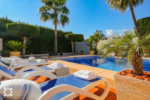 ein Swimmingpool mit Liegestühlen und ein Swimmingpool in der Unterkunft Villa Aurora by Abahana Villas in Benissa