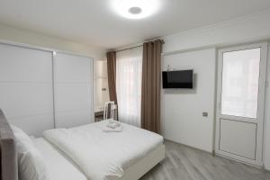 biała sypialnia z łóżkiem i telewizorem w obiekcie Apartament in the Center Area w mieście Sectorul Botanica