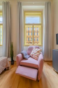 een roze stoel in een woonkamer met een raam bij Historic City Center Deer Suite by Rentez in Praag