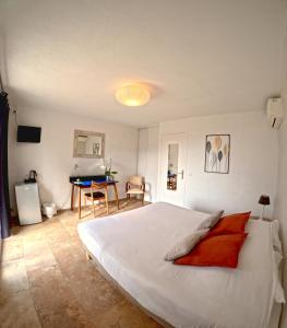 Un dormitorio con una gran cama blanca y una mesa. en Azur Hotel, en Le Lavandou