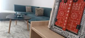 a living room with a blue couch and a table at Logement Chic, résidence azaléa - Alger in Draria