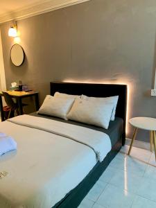 una camera da letto con un letto con lenzuola bianche e un tavolo di Andiana Hotel & Lodge - Kota Bharu City Centre a Kota Bharu