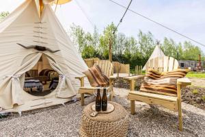 a couple of chairs and a teepee with a tent at Comfort Tipi Marie, Tipi Bo Deluxe & tent Nicolaï - 'Glamping in stijl' in Lembeke
