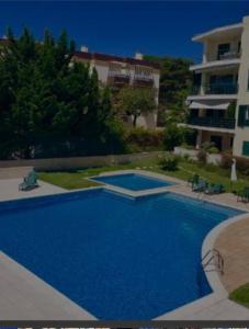 uma grande piscina azul em frente a um edifício em Private room with view em Estoril