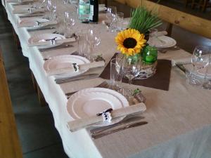 una larga mesa blanca con platos y vasos y un girasol en sodyba Vieversynė en Duokiškis