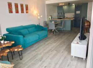 sala de estar con sofá azul y cocina en NUEVO El Faro Beach Marbella, en Marbella
