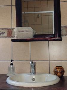 a bathroom sink with a mirror and a towel at Khumbula iAfrica 2 in Marloth Park