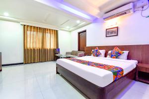 een hotelkamer met een bed en een stoel bij FabHotel Shakti Palace in Ponda